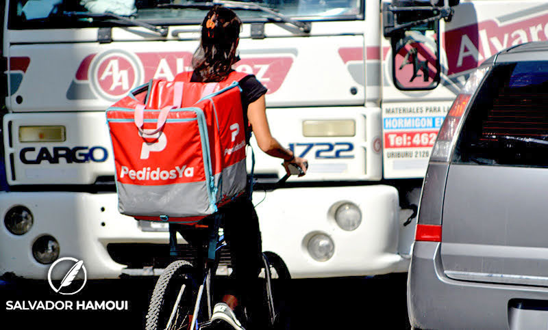 trabajadora de aplicación de pedidosya en bicicleta entre el tránsito